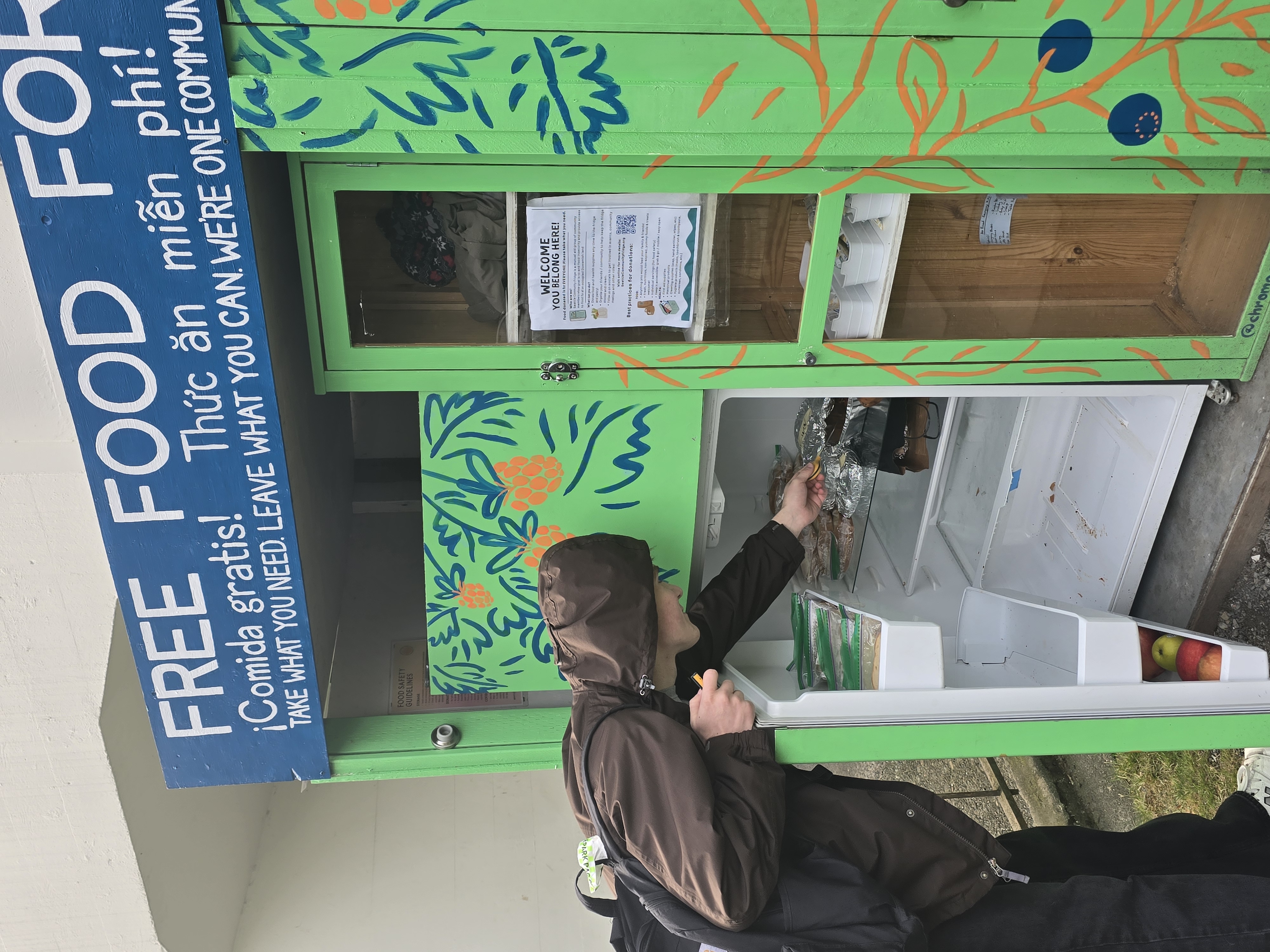 A close-up of the micropantry. A person is opening the refrigerator and reaching down to place something inside.