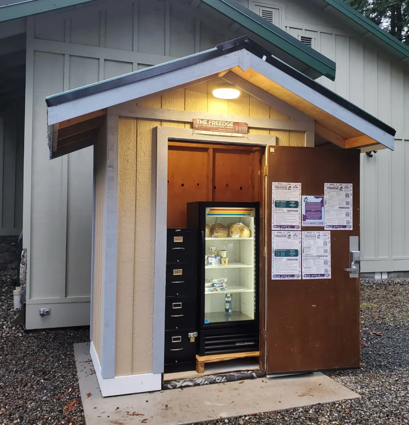 A small covered outbuilding with a small refrigerator and filing cabinet for food storage.